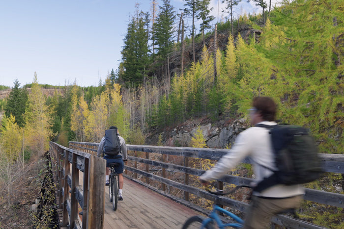 Mountain bikers wearing lightweight shorts riding on a trail, demonstrating summer MTB clothing in action.