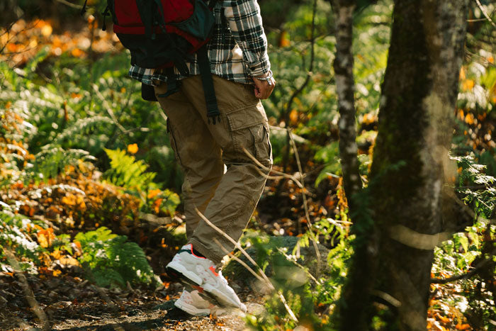Close-up of Moosehill men's technical cargo hiking pants in olive green, showing water-resistant fabric on a rainy forest trail commute.