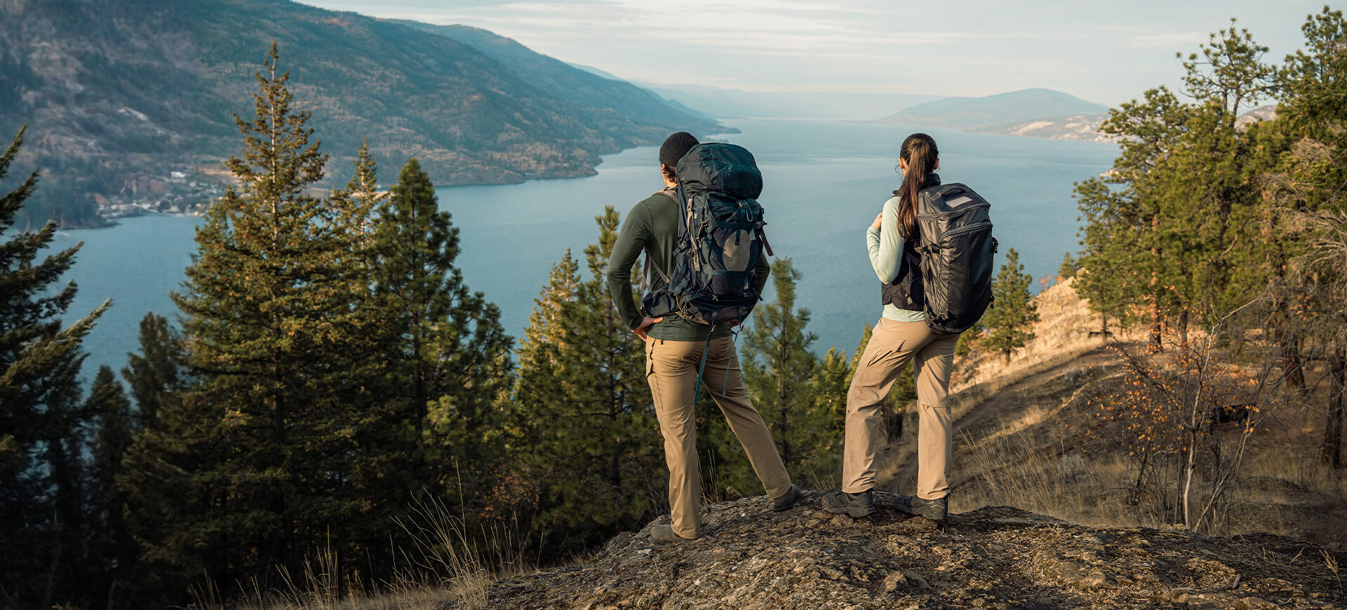 Moosehill durable hiking pants for men and women featured in a scenic mountain landscape with hikers overlooking a lake.